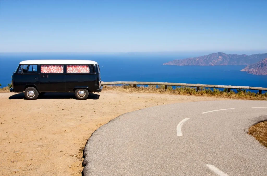 Van vintage garé sur une route côtière face à la mer en Corse