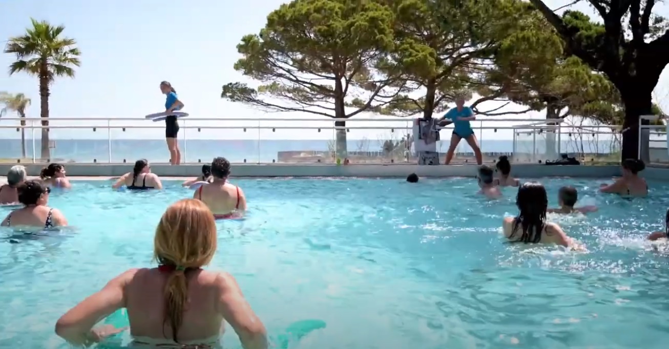 Participants joyeux plongeant dans l'énergie de l'aquagym en plein air au camping Merendella.