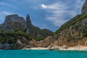 Camping corse bord de mer, plage isolée avec des eaux turquoises entourée de montagnes majestueuses. Lieu idéal pour évasion et détente.