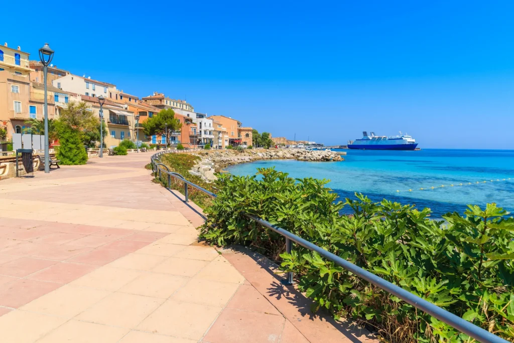 Port de l’Île Rousse – Escale authentique pour vos vacances en camping corse bord de mer Le port pittoresque de l’Île Rousse avec ses bateaux et ses maisons colorées, au bord de la mer.