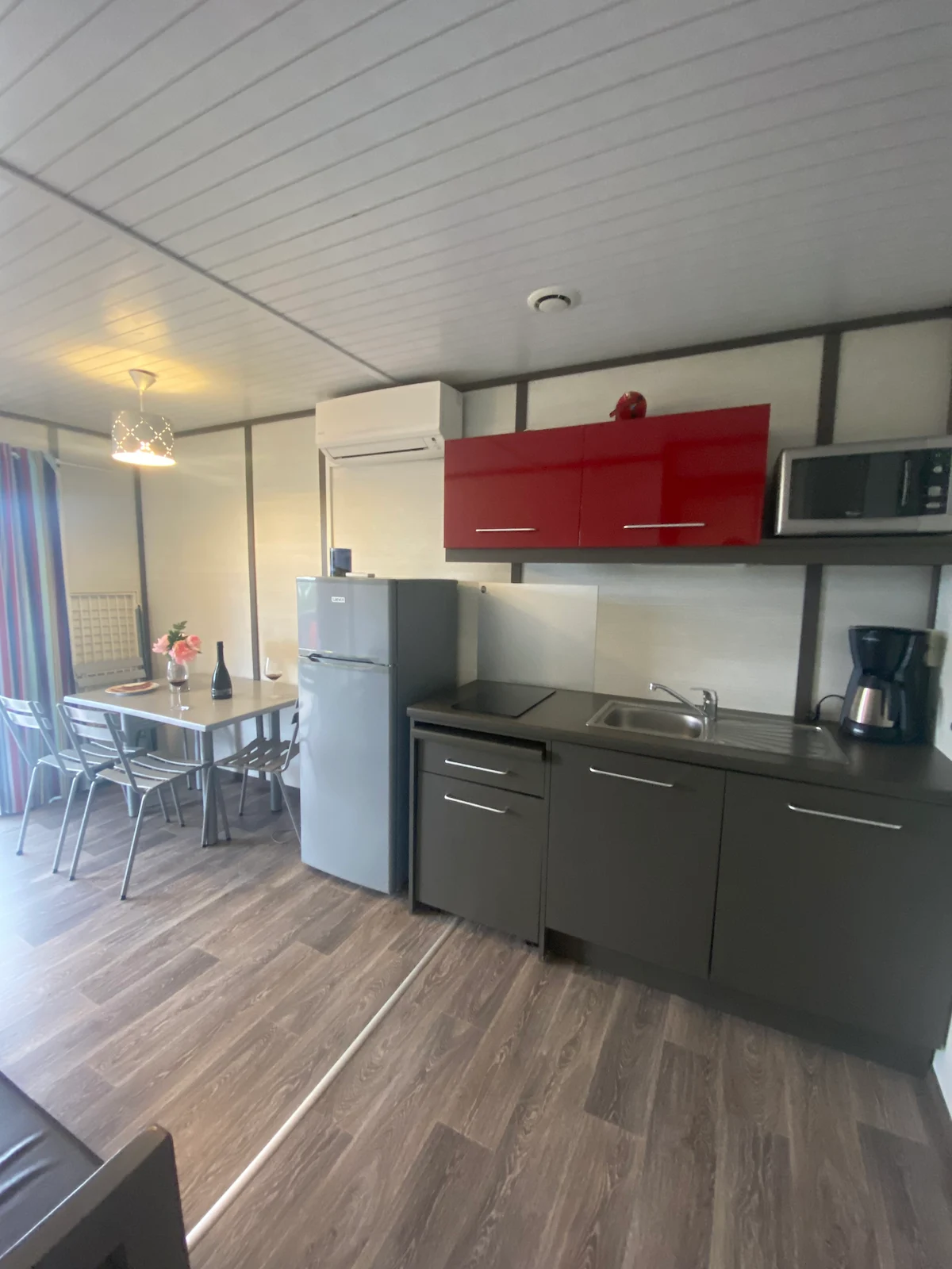 Cuisine moderne aux placards rouges entièrement équipée dans un hébergement locatif du Camping Villata.