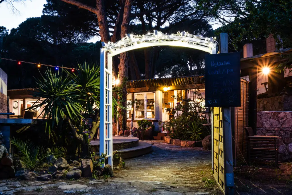 Arche lumineuse à l'entrée du restaurant du Camping Villata, décorée de guirlandes pour une ambiance de soirée estivale.
