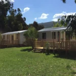 Alignement de mobil-homes neufs sur une pelouse verdoyante avec vue panoramique sur les montagnes corses.