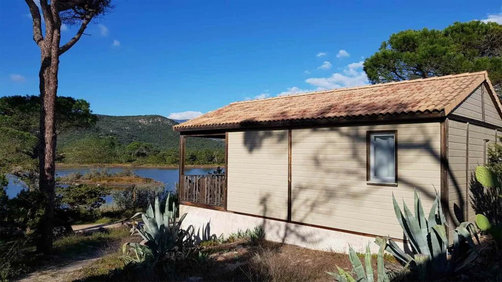 mobilhome-vue-etang-camping-calme-Villata Extérieur d'un chalet climatisé au Camping Villata, entouré d'agaves et offrant une vue dégagée sur l'étang.