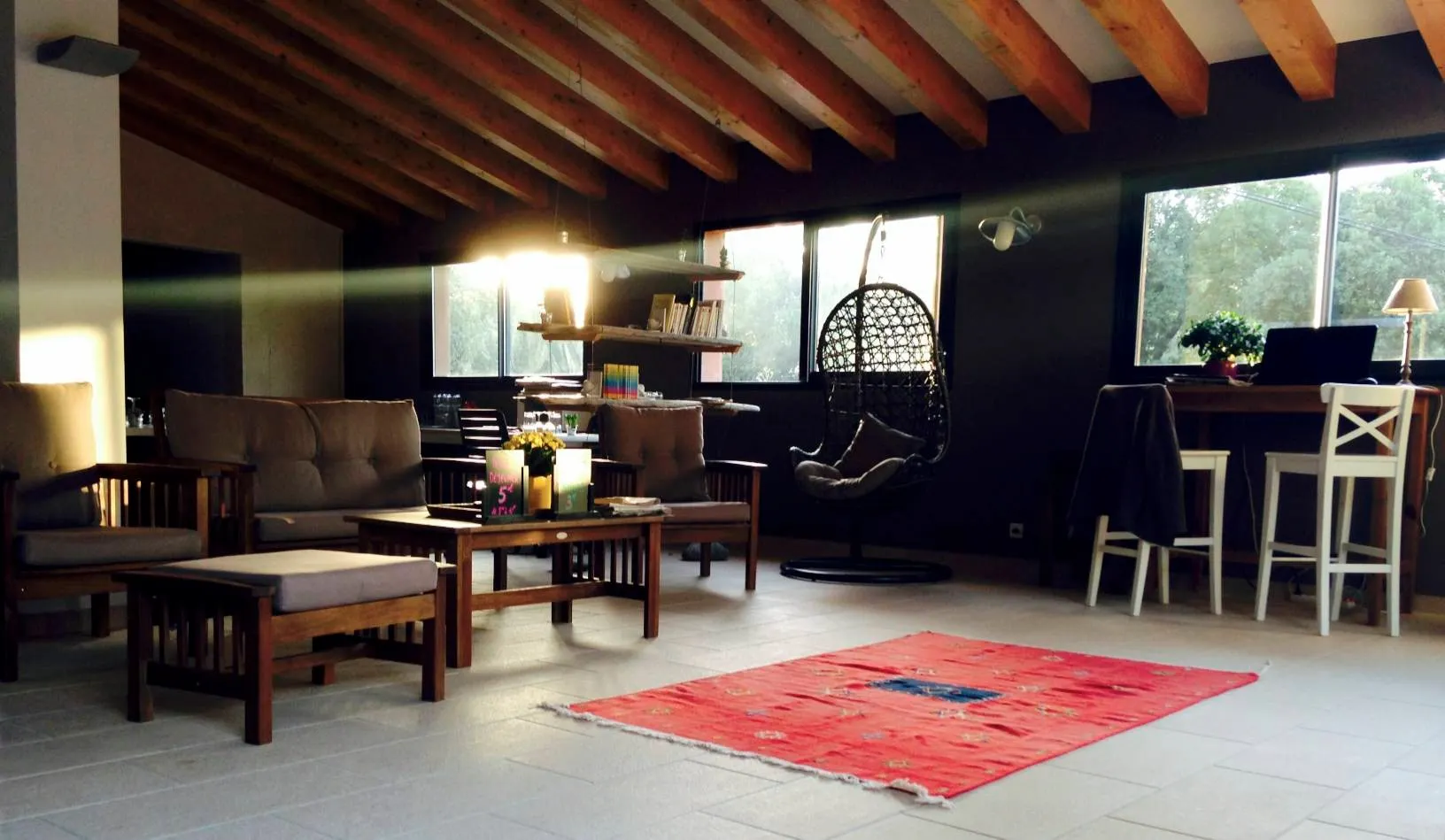 Intérieur de la salle de repos avec canapés confortables, poutres apparentes, coin lecture et espace de travail pour le wifi.